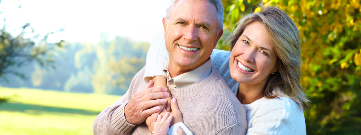 Happy senior couple smiling and embracing outdoors in autumn